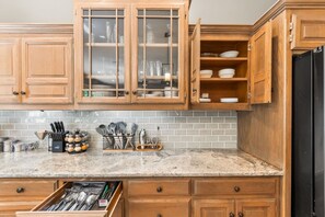 A kitchen with wooden cabinets, a marble countertop, and a black refrigerator. - Creekside Lodge 6bd 22 acres (Stilwell)