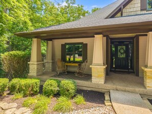 A house with a covered porch, two rocking chairs, and a well-maintained garden.