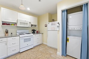 Une cuisine avec des meubles blancs, une cuisinière, un four à micro-ondes et un réfrigérateur.