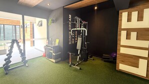 Uma academia com um suporte para agachamento, banco de musculação e uma parede com frases motivacionais.