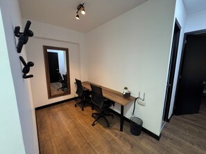 A modern office space with a wooden desk, black office chairs, a large mirror, and a small potted plant. - 2-Bedroom Apartment with Heated Pool & Gym - Aparts4Days (San Isidro)