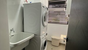 Uma área de lavanderia compacta, com máquina de lavar, secadora e pia.