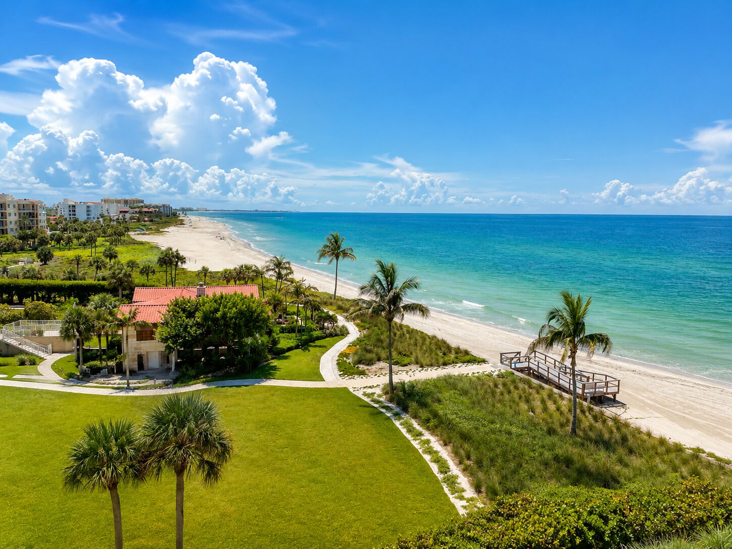A coastal resort with a beach, palm trees, and a clear blue sky.
