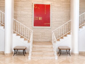 A staircase with white railings and beige steps, leading to a red framed artwork on a brick wall. - 2 bedroom 2 bath Luxury Beachfront condo on Longboat Key (Longboat Key)