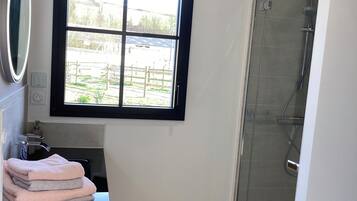 Ein Badezimmer mit Fenster, Spiegel, Waschbecken und Dusche.