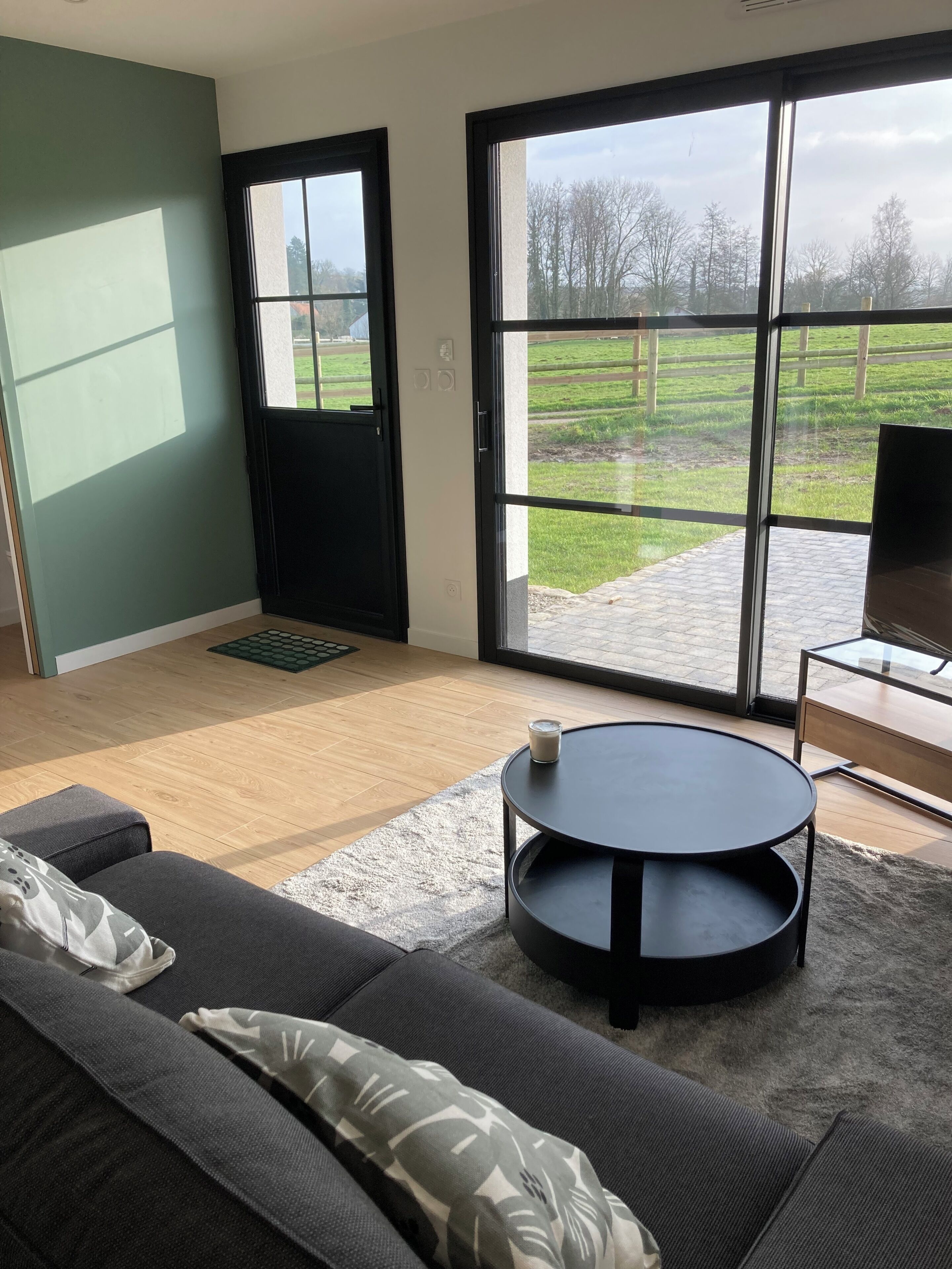 Un salon moderne avec un canapé, une table basse ronde et un téléviseur posé sur un meuble.