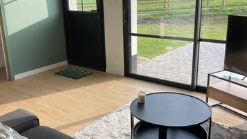 Un salon moderne avec un canapé, une table basse ronde et un téléviseur posé sur un meuble.
