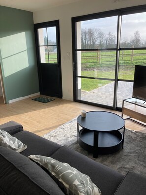 Ein modernes Wohnzimmer mit einer Couch, einem runden Couchtisch und einem Fernseher auf einem Schrank.