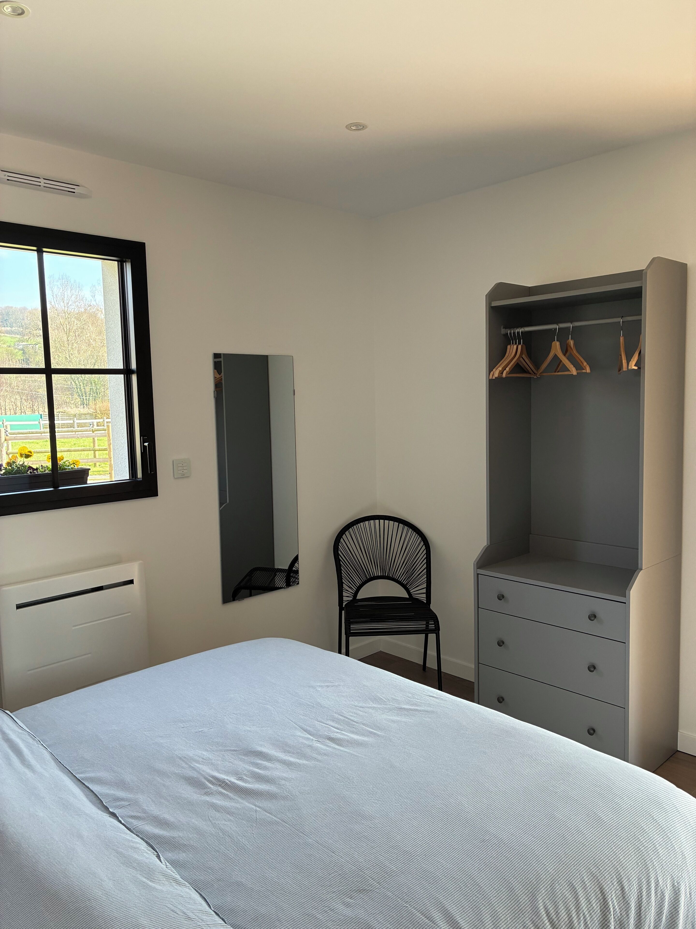 Ein Schlafzimmer mit Bett, Kleiderschrank, Stuhl und Fenster.