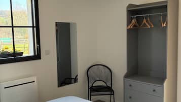 Een slaapkamer met een bed, een kledingkast, een stoel en een raam.