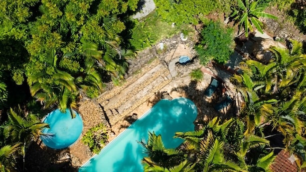 An aerial view of a resort with a swimming pool surrounded by lush greenery and a stone pathway. - Cabanas VillaRejo (Jarinu)