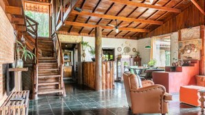 A spacious interior with a staircase leading to an upper level, a seating area with a sofa, and a bar area with a counter. - Cabanas VillaRejo (Jarinu)
