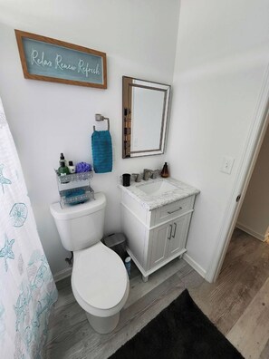 Ein Badezimmer mit Toilette, Waschbecken, Spiegel und Handtuchhalter.