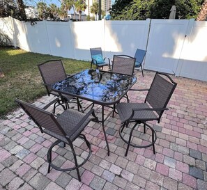 Eine Terrasse im Freien mit einem Glastisch, umgeben von sechs Stühlen.