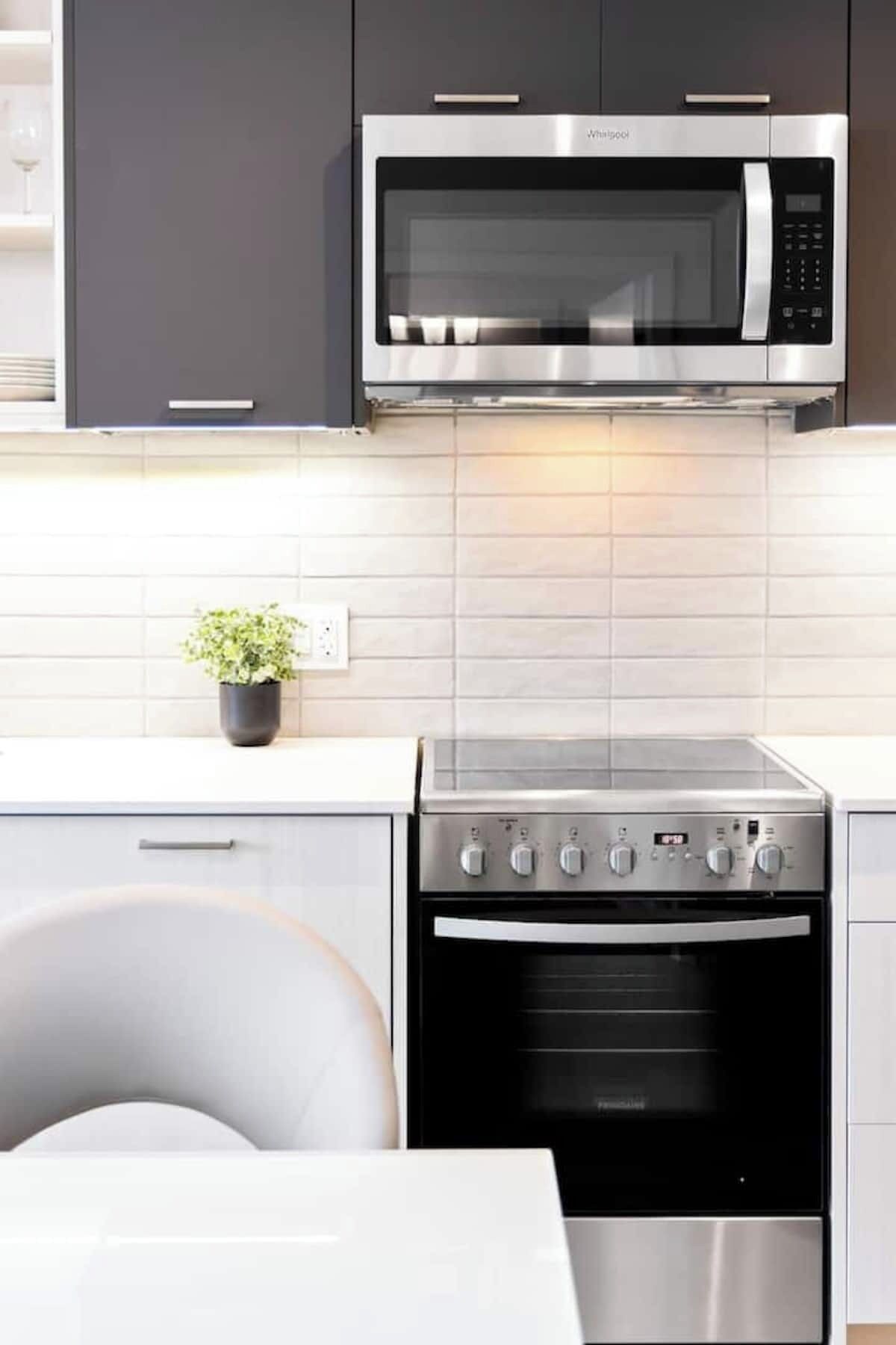Une cuisine moderne équipée d’un four à micro-ondes, d’un four traditionnel et d’une plaque de cuisson.