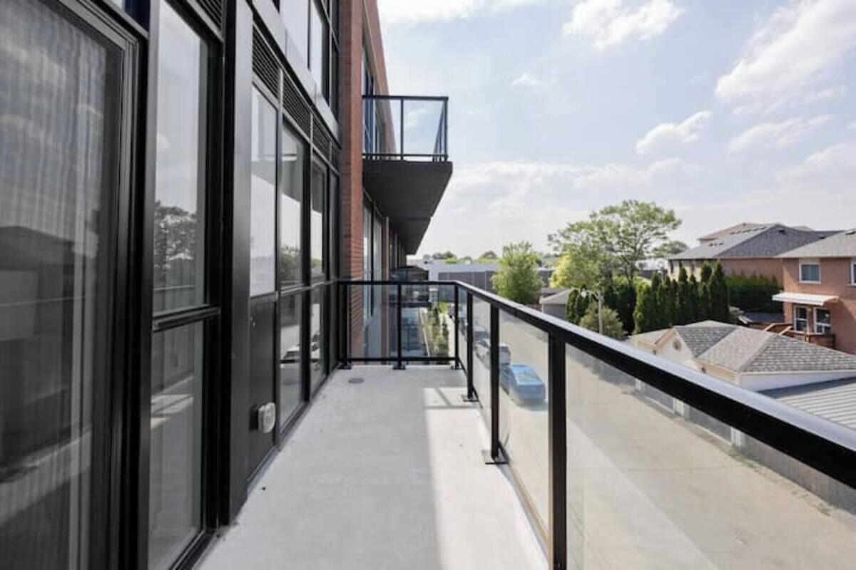 A balcony with a glass railing overlooking a residential area.