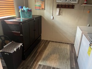 A compact kitchen with a refrigerator, a wooden cabinet, and a small trash bin. - 3-bedroom house in awesome Clearwater with everything Tampa Bay area can offer. (Clearwater)