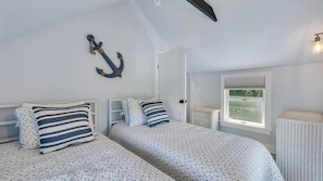 A bedroom with two beds, nautical-themed decor, a window, and a radiator. - Charming Mattituck Retreat Near the Bay with Modern Updates (Mattituck)