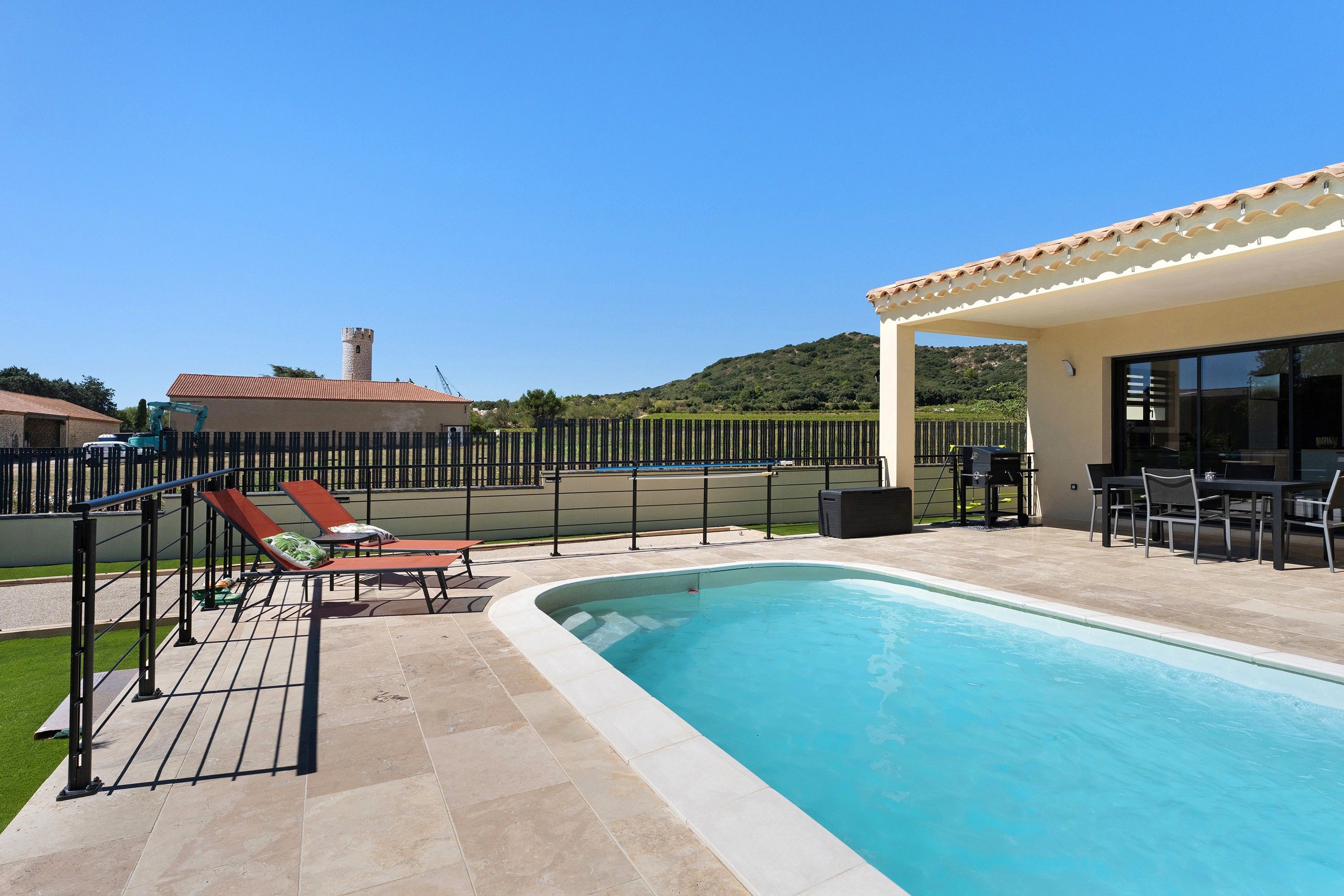 Une piscine avec des chaises longues et un espace patio couvert.