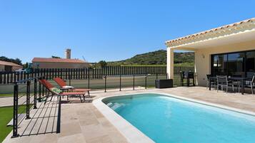 Une piscine avec des chaises longues et un espace patio couvert.