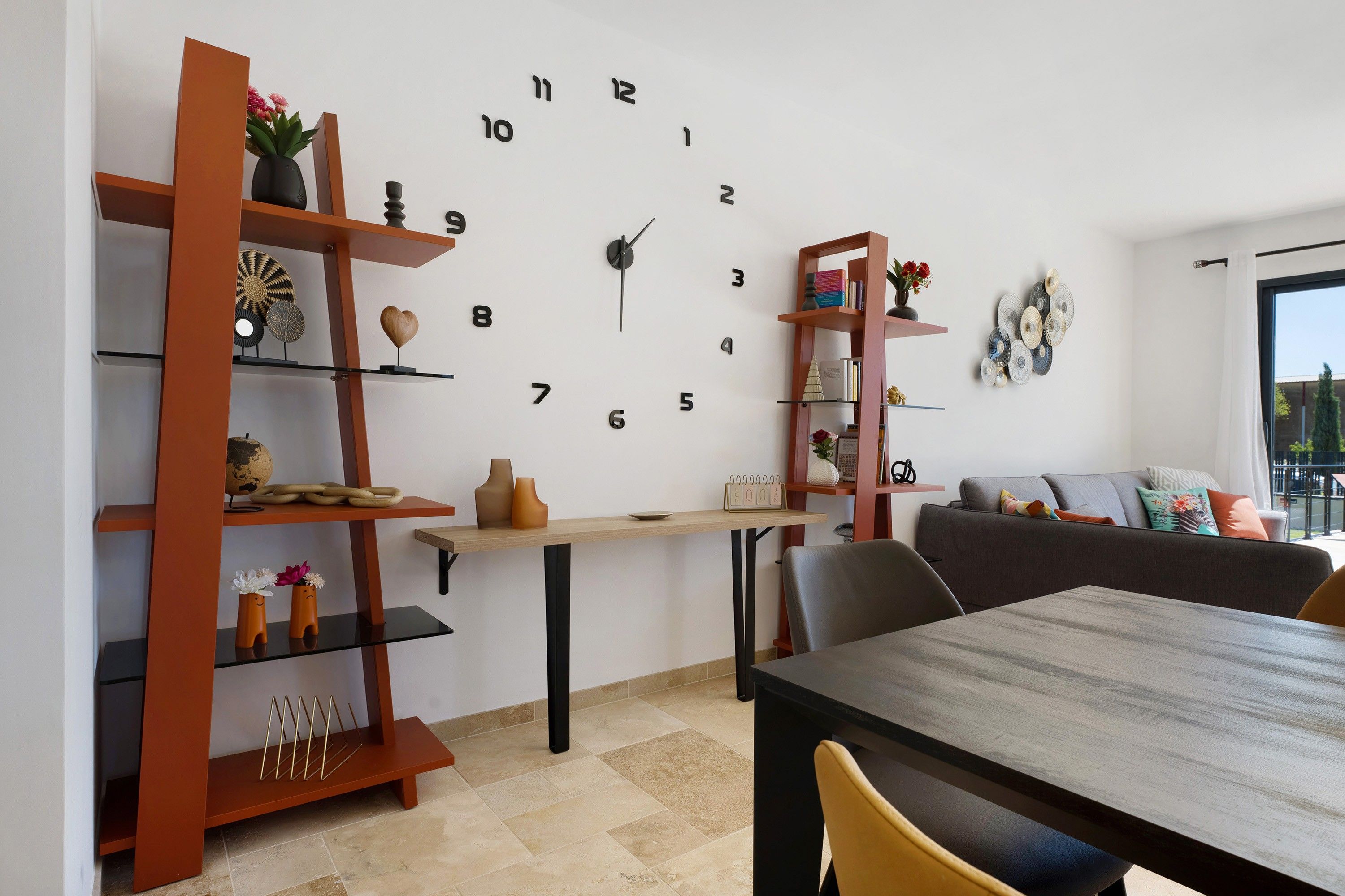 Un salon moderne avec une grande horloge murale, des étagères en bois, une table à manger et un canapé.