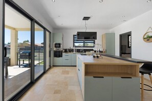 Una cocina moderna con una isla grande, puertas correderas de vidrio que dan a un área exterior y vistas del paisaje circundante.