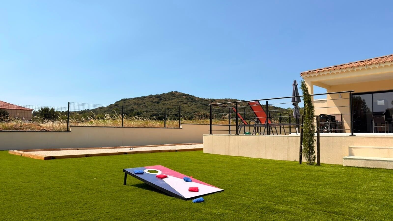 Una superficie plana con un diseño colorido, una zona con césped y un edificio con tejado de baldosas.