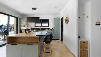 A modern kitchen with a central island, bar stools, and a large window.