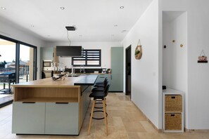 A modern kitchen with a central island, bar stools, and a large window.
