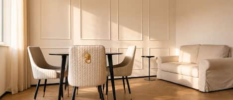 A room with a wooden floor, a white sofa, two armchairs, and a small table.