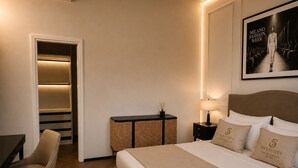 A hotel room with a bed, a desk, a chair, a nightstand, a lamp, and a framed picture on the wall. - Five Suites 1 (Milan)