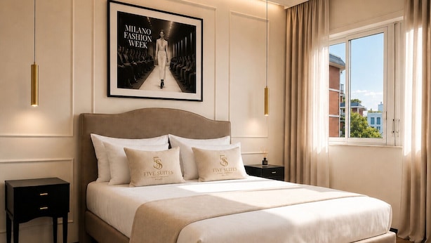 A hotel room with a large bed, a framed poster on the wall, a nightstand, and a window with curtains. - Five Suites 1 (Milan)