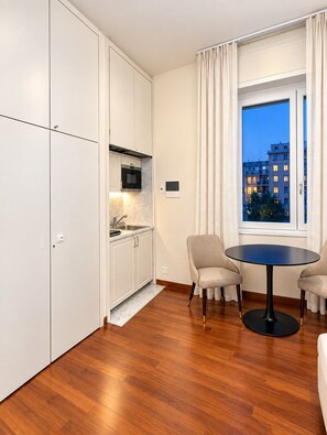 A modern kitchen with white cabinets, a built-in oven, and a window with curtains. - Five Suites 1 (Milan)
