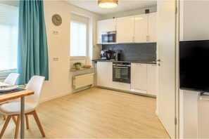 A compact kitchen with white cabinets, a microwave, an oven, and a coffee maker. - Hochwertiges Apartment - Residenznähe, Parken (Würzburg)