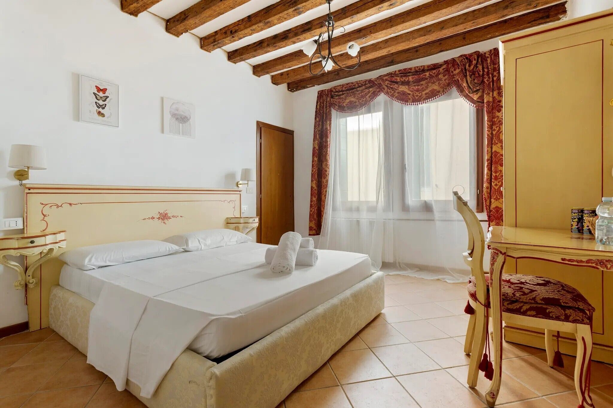Une chambre d’hôtel avec un lit, un bureau, une chaise et une fenêtre avec des rideaux.