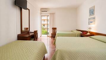 A hotel room with two beds, a desk, a chair, a television, and a window with a view of a balcony.