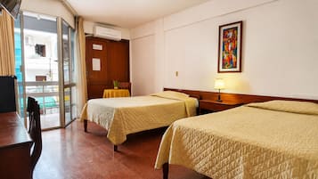 Habitación de hotel con dos camas, una mesa, una silla, un equipo de aire acondicionado y un cuadro en la pared.