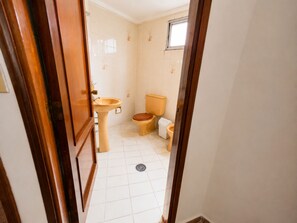Uma casa de banho com sanita, lavatório e janela.