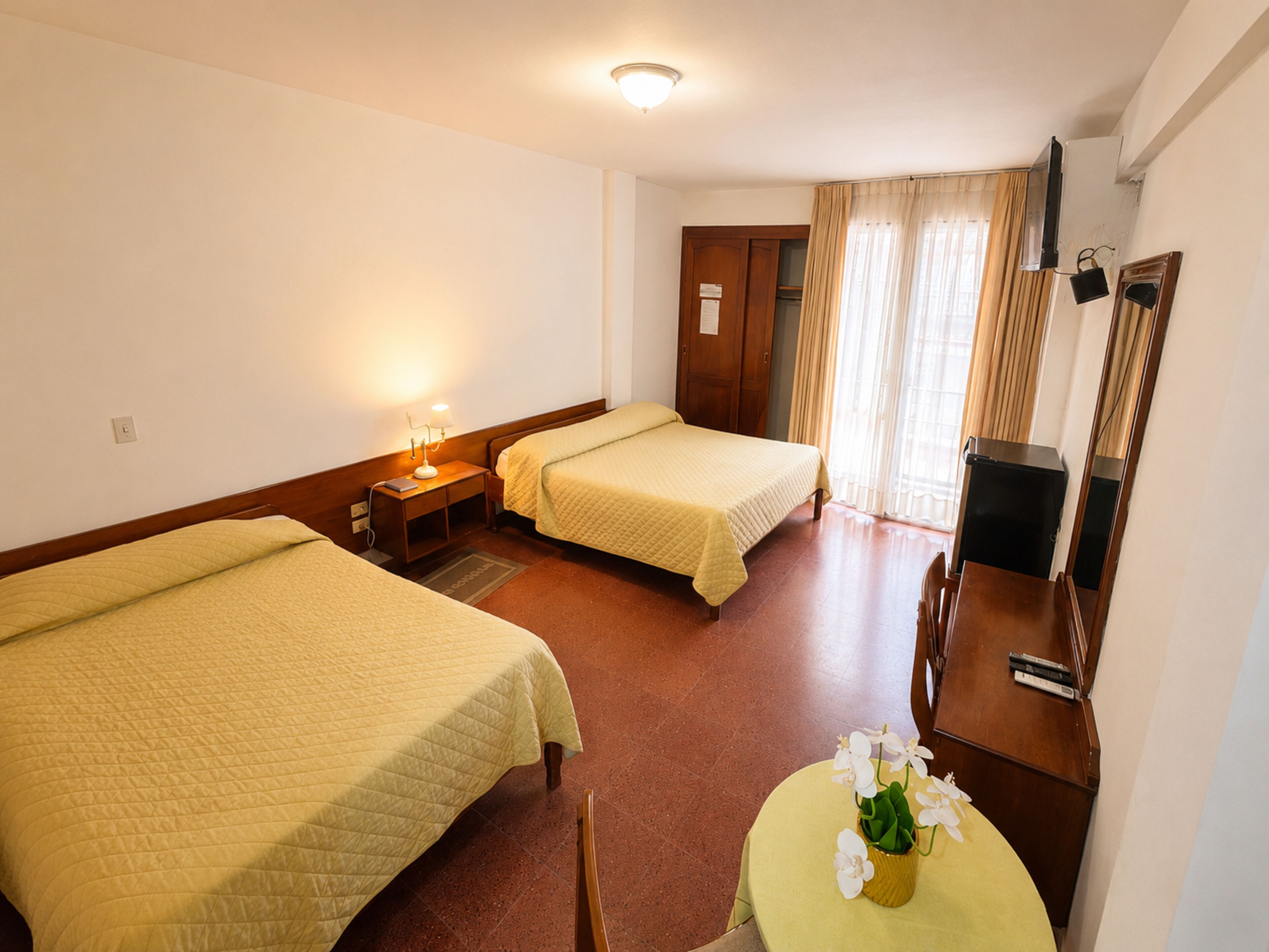 Une chambre d’hôtel avec deux lits, un bureau, une chaise, une télévision et un miroir.
