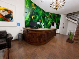 A reception desk with a monitor, a trash can, and a plant.