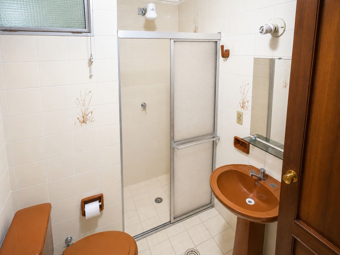 Un baño con ducha, inodoro, lavamanos y espejo.
