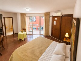 Habitación de hotel con cama, una mesa con flores, vistas al exterior y un armario.