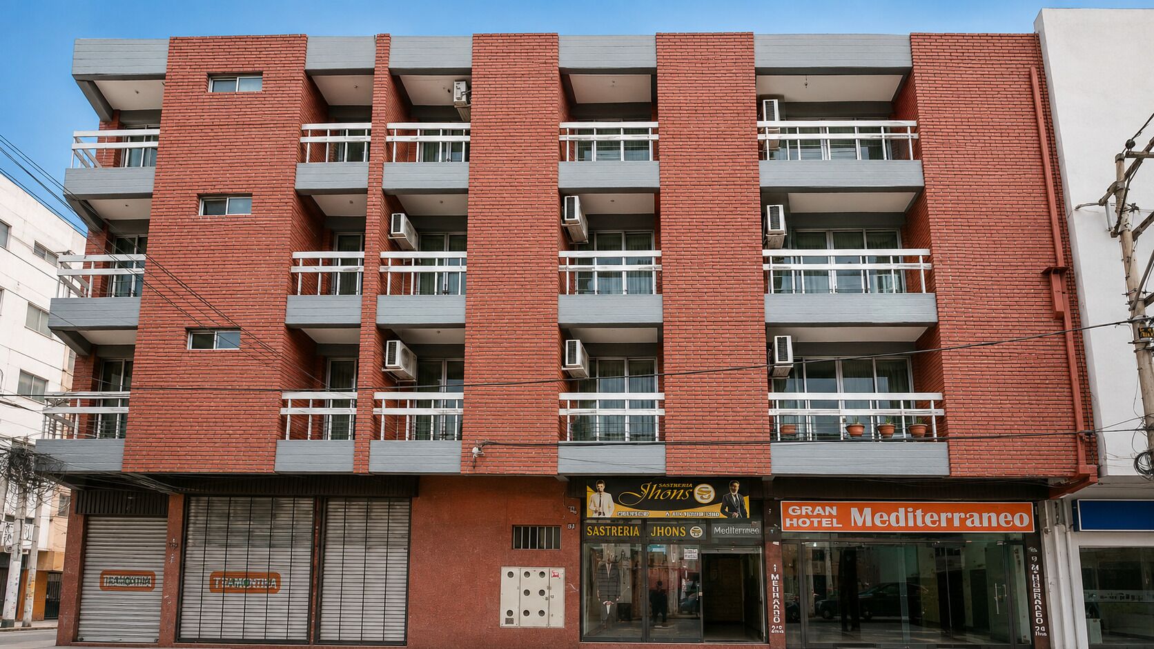 A multi-story hotel with balconies, air conditioning units, and a storefront with signage.