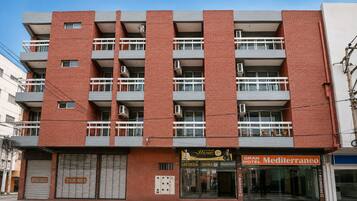 A multi-story hotel with balconies, air conditioning units, and a storefront with signage.