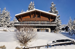 Eine Holzhütte mit geneigtem Dach, umgeben von schneebedeckten Bäumen.