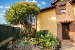 A residential property with a brick exterior, a small garden with a pond, and a wooden door.