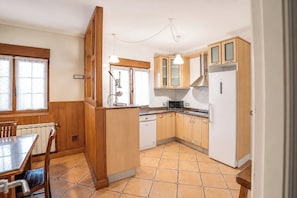 A kitchen with wooden cabinets, a microwave, a dishwasher, and a dining area with a table and chairs. - Vacation home with a private pool and garden, a barbecue, and close to beaches. (Arce)