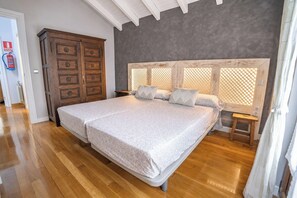 Un dormitorio con una cama grande, un armario de madera y un techo con vigas a la vista.