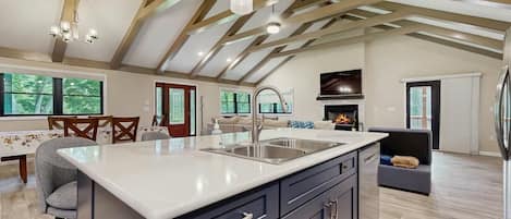 A spacious kitchen with a large island, modern appliances, and a high ceiling with exposed beams.