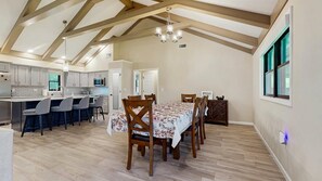 Una cocina amplia con comedor, vigas de madera en el techo y un ventanal grande.